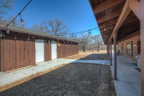 A wooden cabin with a covered porch, a door, and a small outdoor area. - Luxury Cabin Hot-Tub & GameRoom-Wheelchair Access! (Fredericksburg)
