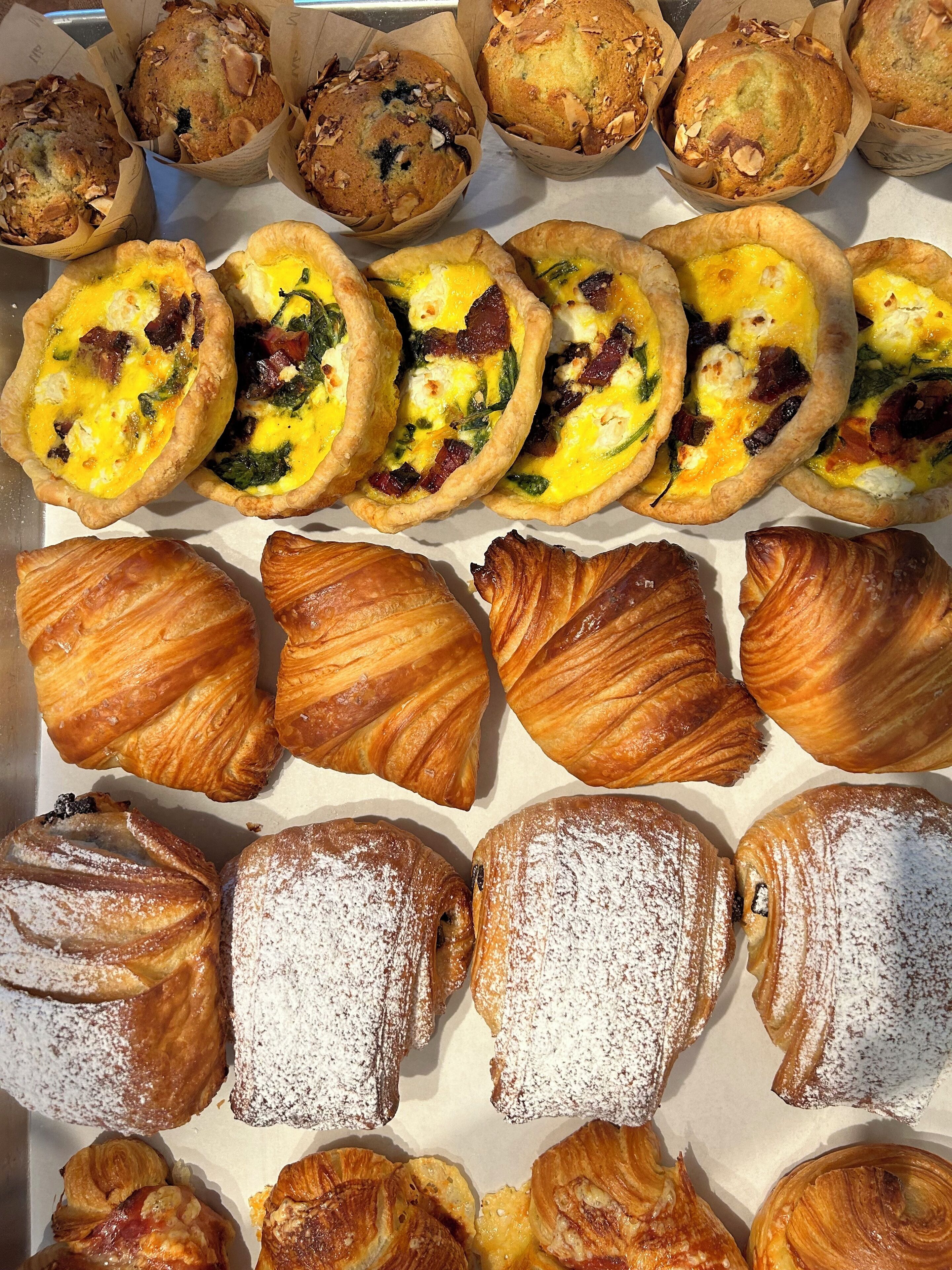 A variety of baked goods including muffins, quiches, and pastries.