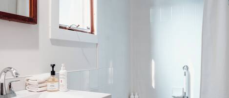 A modern bathroom with a white sink, mirror, and shower area.