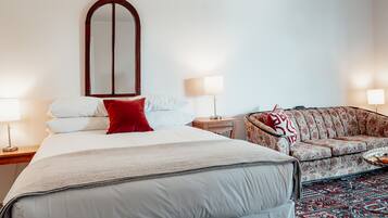 Ett hotellrum med en stor säng, en soffa, en spegel och två sänglampor.