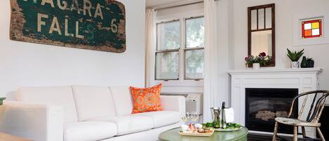 A living room with a white sofa, a green coffee table, a fireplace, and a large sign reading "NIAGARA FALLS".