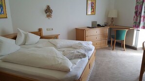 Ein Hotelzimmer mit Bett, Schreibtisch mit Stuhl, Lampe und Telefon.