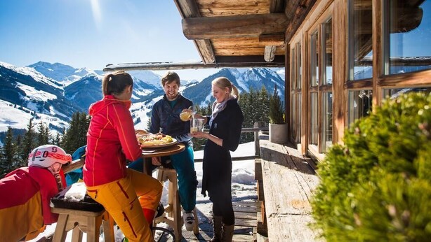 Une cabane en bois avec un coin repas donnant sur des montagnes enneigées.