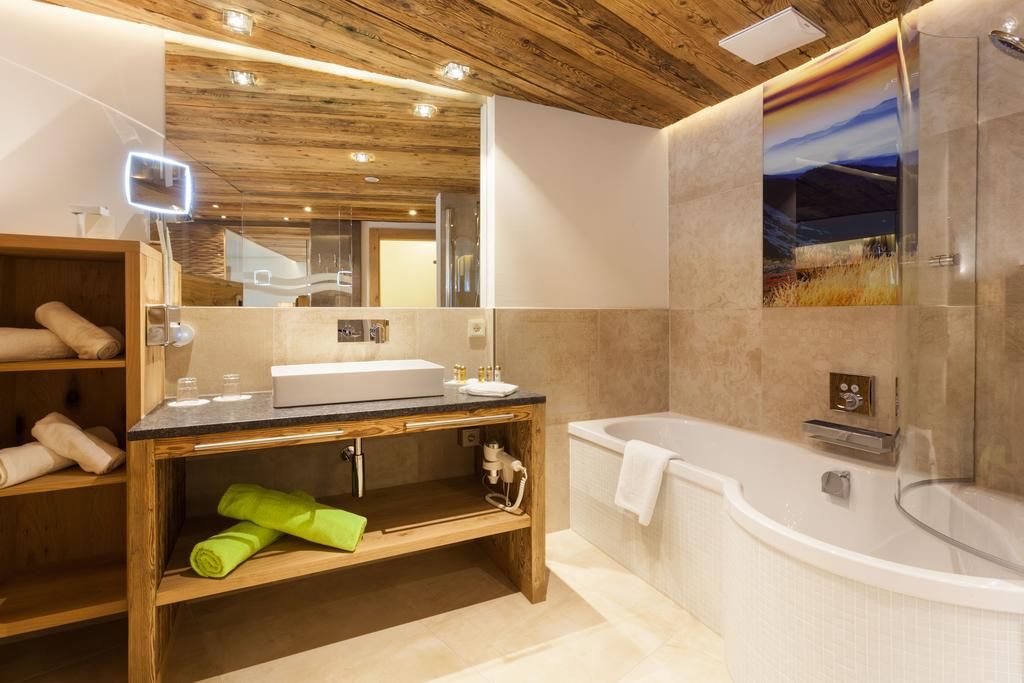 A modern bathroom with a wooden vanity, a large mirror, a bathtub, and a shower area.