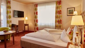 Ein Hotelzimmer mit einem Bett, einem Schreibtisch, einem Stuhl, einem Fernseher und einer Lampe.