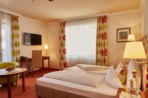 Ein Hotelzimmer mit einem Bett, einem Schreibtisch, einem Stuhl, einem Fernseher und einer Lampe.