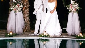 Una ceremonia de boda junto a una piscina, con arreglos florales y velas.
