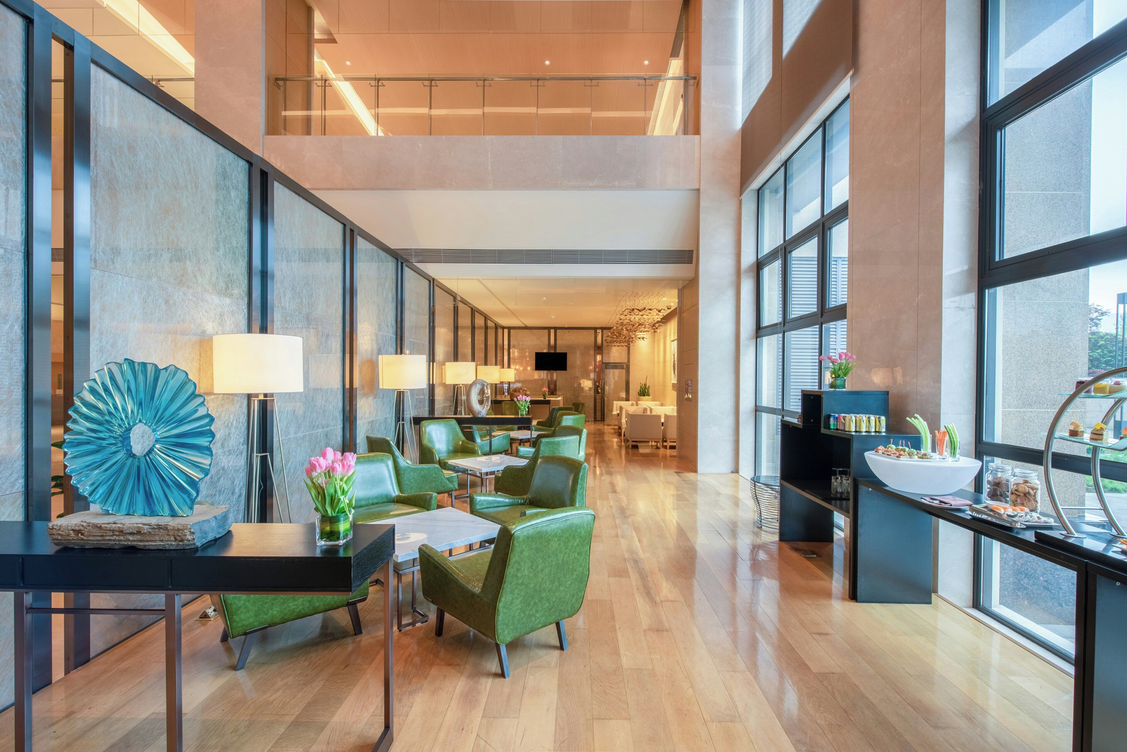 Un amplio vestíbulo de hotel con techo alto, ventanas grandes y un diseño de interiores moderno.