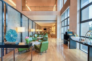 Eine großzügige Hotelhalle mit hoher Decke, großen Fenstern und einem modernen Interior-Design.