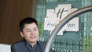 A person holding a luggage cart near a wall with a sign that reads "Holiday Inn".