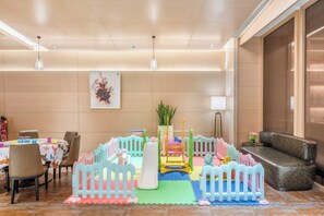 Ein Spielbereich für Kinder mit Rutsche, Schaukeln und weichen Spielmatten.