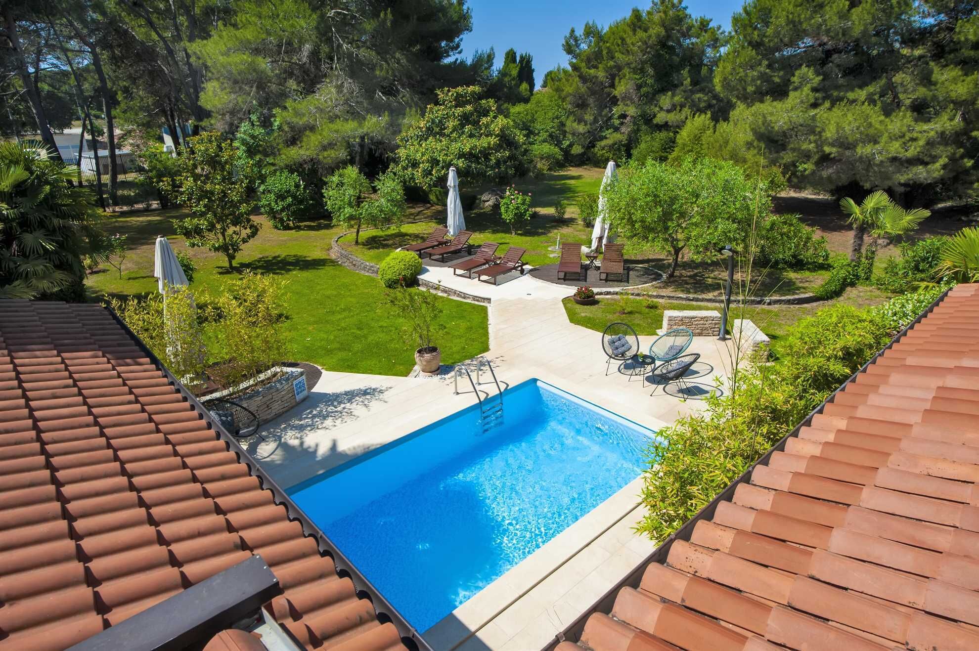 A rooftop swimming pool with a clear blue pool, surrounded by a patio area with lounge chairs and umbrellas.