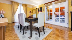 Un coin repas avec une table en bois, des chaises blanches et un tapis à motifs.