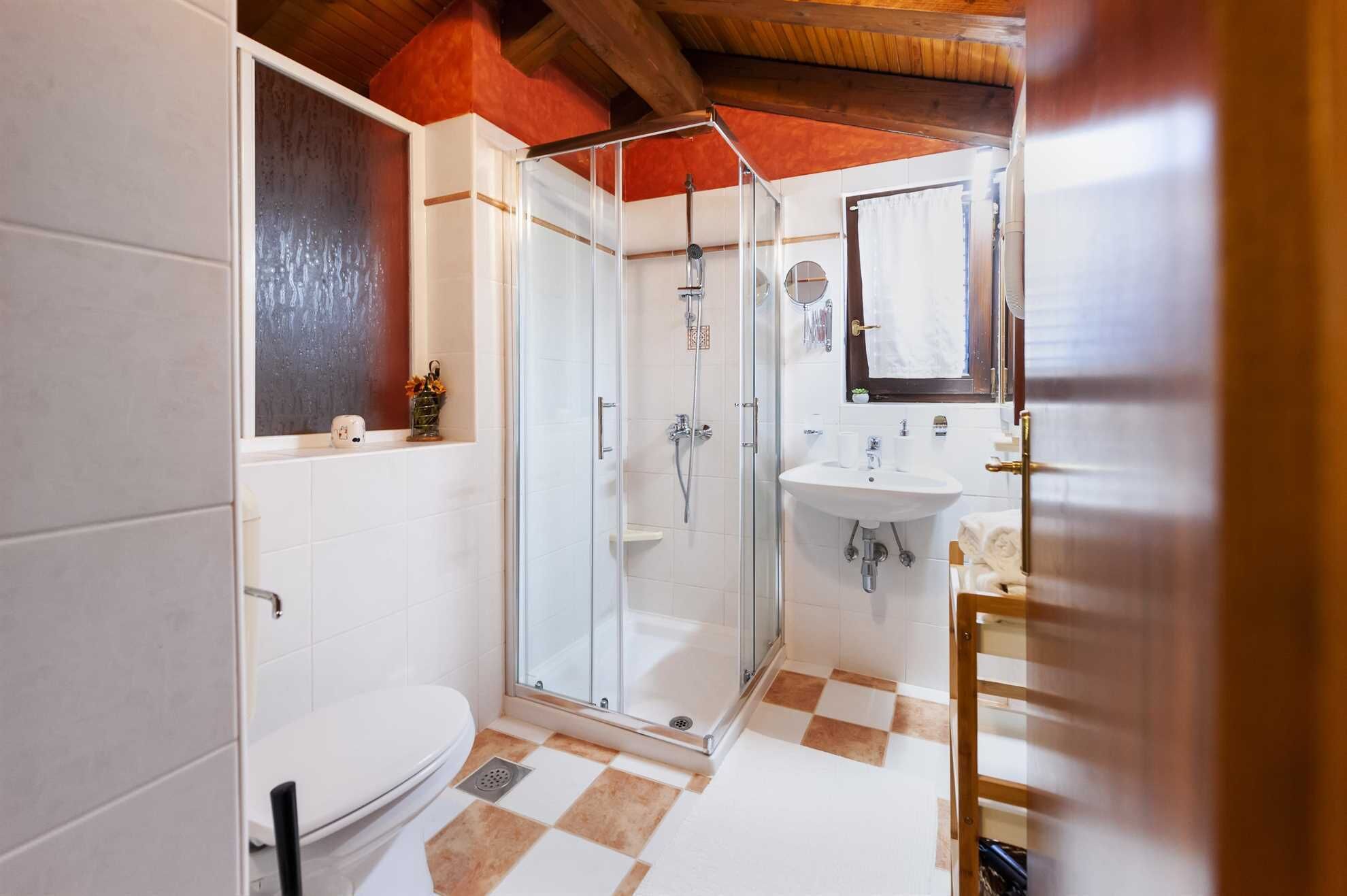A bathroom with a glass-enclosed shower, a white sink, and a toilet.