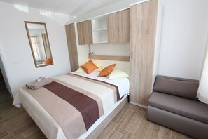 A neatly arranged bedroom with a bed, a sofa, a mirror, and built-in wooden cabinets. - PINA Studio 3 with terrace (Rovinj)