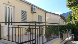 A building with a balcony, a staircase, and a view of mountains.