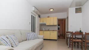 A compact living space with a sofa, dining table, chairs, and a kitchenette. - VILLA ALEX  One-Bedroom Apartment (ANA) (Podaca)