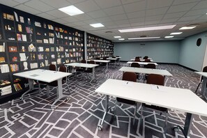A conference room with white tables, black and white patterned carpet, and a wall decorated with various items. - Village Hotel Nottingham (Nottingham)