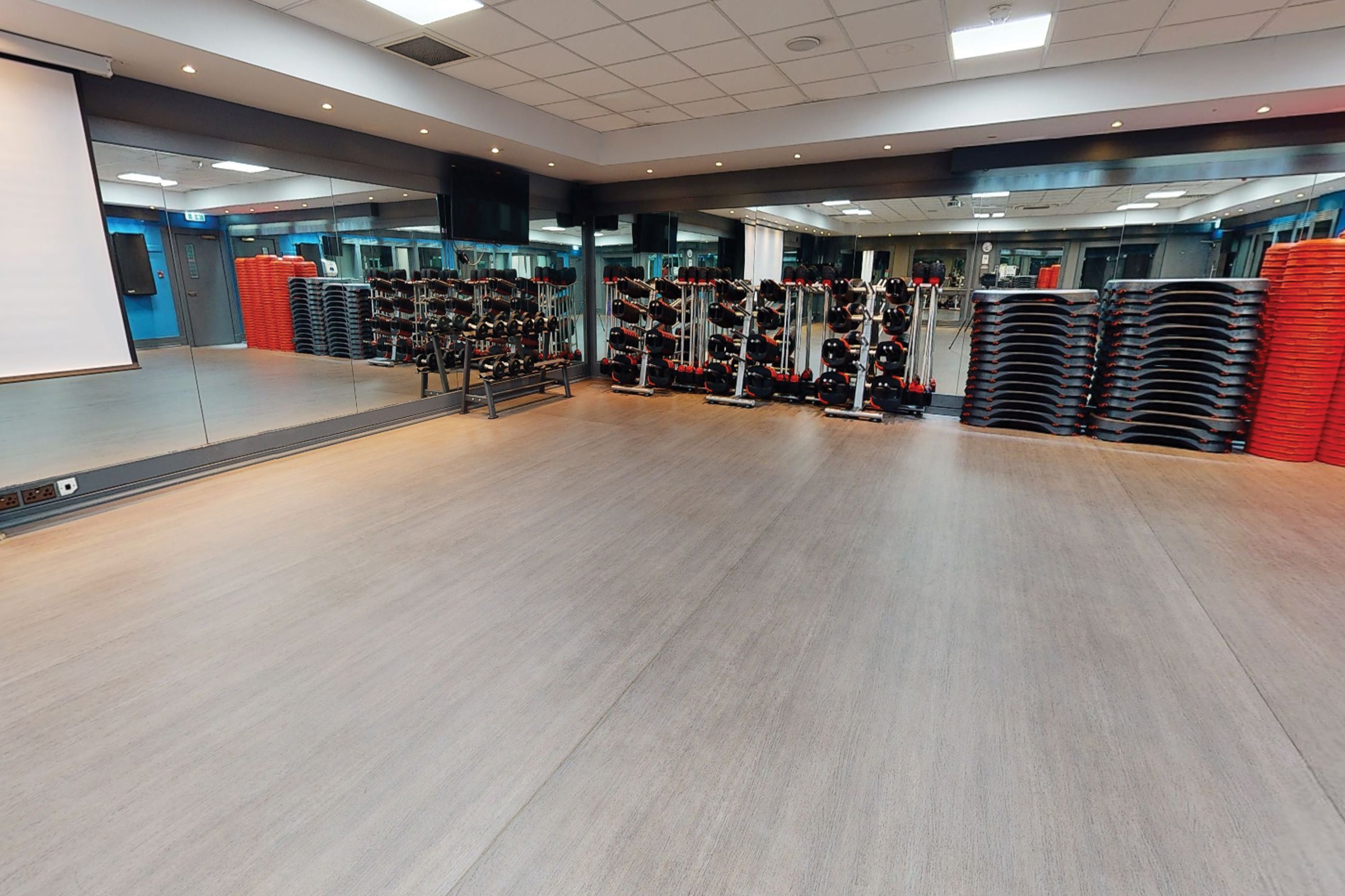 Une salle de sport spacieuse équipée de matériel de musculation et de miroirs.