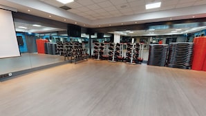 Ein geräumiger Fitnessraum mit Krafttrainingsgeräten und Spiegeln.
