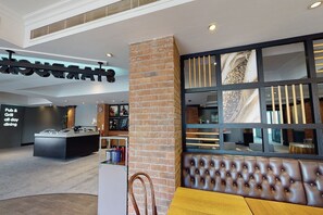 Un interior moderno con zona de pub y parrilla, un pilar de ladrillo y un área de asientos con vistas.