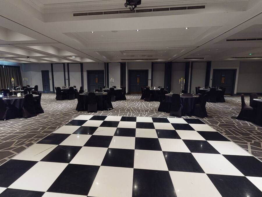 A large room with a checkered floor, multiple tables with chairs, and a stage area.