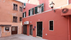 Una calle estrecha con edificios que tienen balcones, una puerta y un letrero.