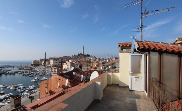 A view of a coastal town with a marina, buildings with terracotta roofs, and a balcony with a satellite dish. - ZARA One-Bedroom Apartment (Rovinj)