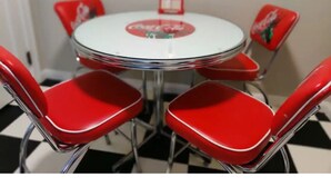 Mesa redonda con superficie blanca y sillas rojas que llevan un logotipo rojo.