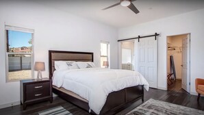 Une chambre à coucher avec un lit, une table de chevet et un ventilateur de plafond.