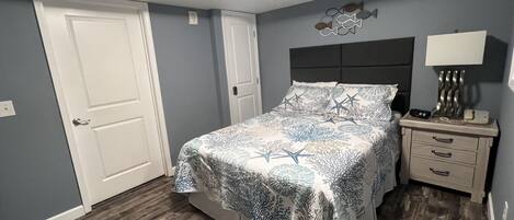 A bedroom with a bed, a nightstand, a lamp, and a wall decoration.