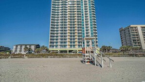 Un grand hôtel doté de nombreux balcons, situé près d’une plage.