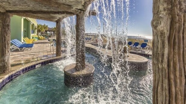 Un espace piscine doté de jets d’eau, de chaises longues et offrant une vue sur l’océan.