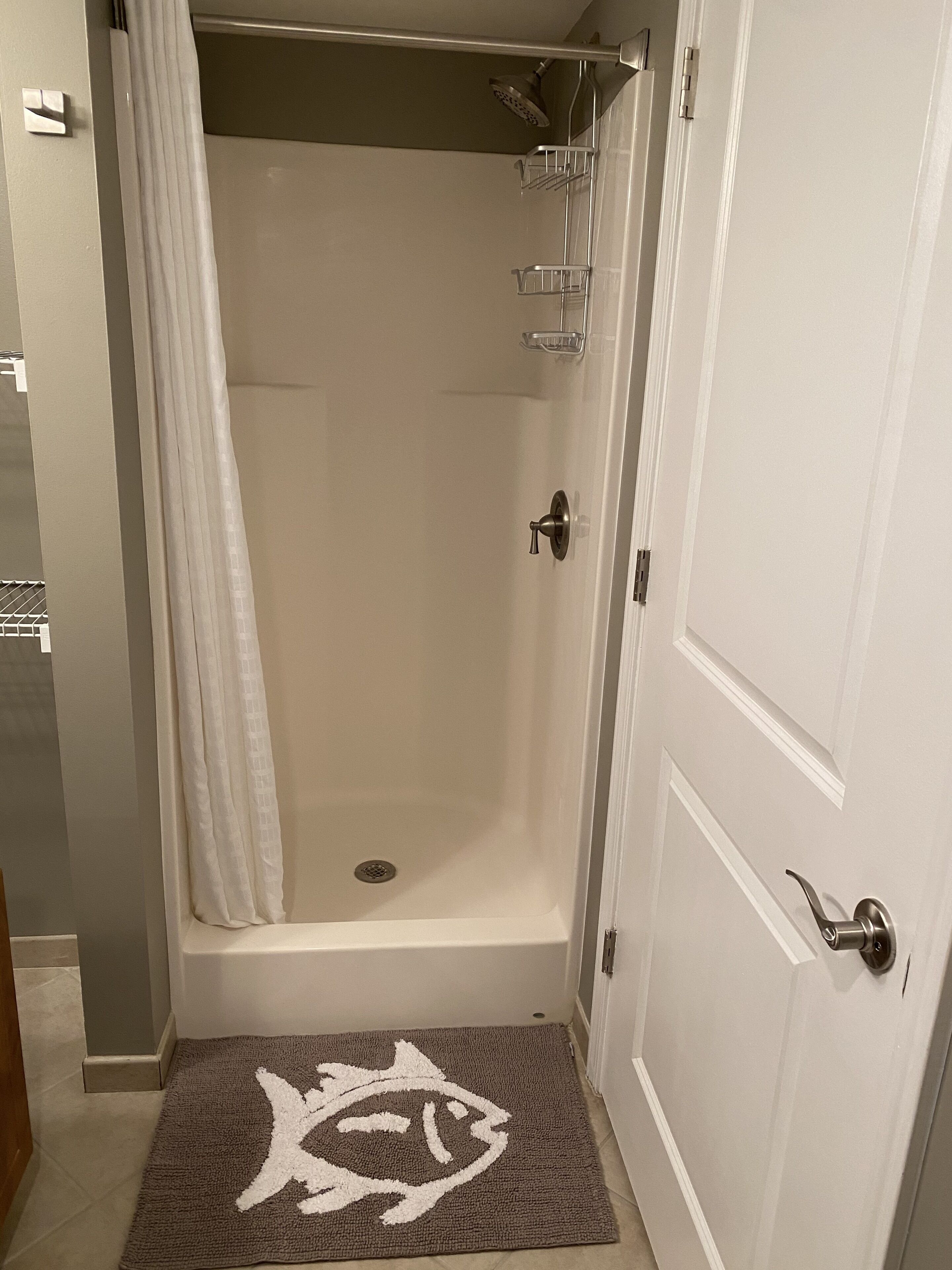 A bathroom with a shower, a towel rack, and a door with a handle.