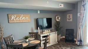 Un coin repas comprenant une table en bois, des chaises, un téléviseur et des objets de décoration.