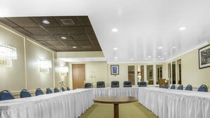 Un salón de conferencias con una larga mesa, sillas azules y una mesa de madera en el centro.