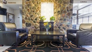 Un área de descanso con paredes de piedra, dos sillones de cuero, una mesa de centro y un jarrón con girasoles.