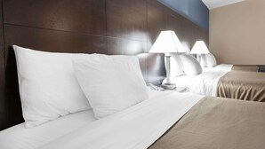 Una habitación de hotel con una cama grande, dos lámparas de noche y un cabecero.
