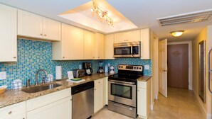 A modern kitchen with white cabinets, a stainless steel dishwasher, a double oven, a microwave, and a tiled backsplash. - Hollywood Beach Tower (Hollywood)