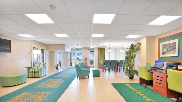 A hotel lobby with a reception desk, seating area, and a green carpet with 'HOTEL CENTER' text. - Hollywood Beach Tower (Hollywood)