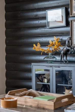 Cozy retreat with a rustic feel, featuring a log wall, framed artwork, and a decorative cabinet.