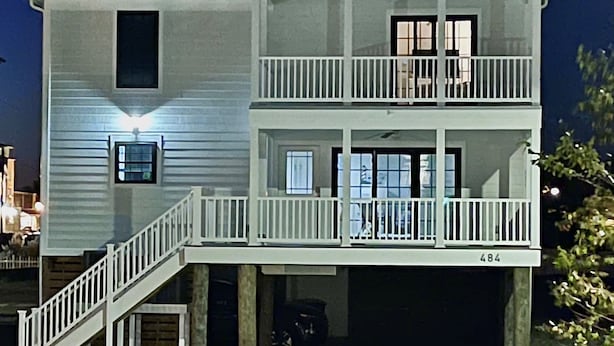 A two-story building with a balcony on the second floor, a garage door, and a visible address number. - 484 E Market - New construction close to town and the Beach! (Lewes)