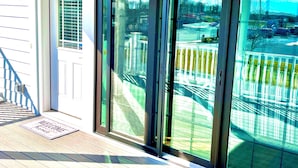 A sliding glass door leading to a balcony with a view of a parking lot and a building in the background. - 484 E Market - New construction close to town and the Beach! (Lewes)