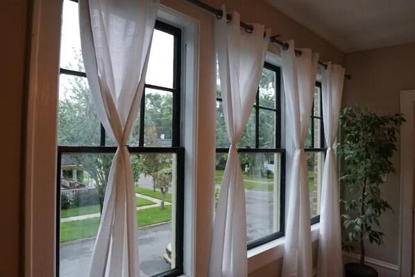 A room with large windows, white curtains, and a potted plant. - Avonly Place Convenient Historic Hideaway (Jacksonville)