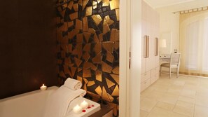 A modern bathroom with a geometric mosaic wall, a bathtub with candles, and a visible shower area. - Tenuta Monacelle (Monopoli)