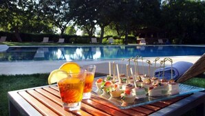 A poolside table with a glass of iced tea, a bottle of water, and a tray of appetizers. - Tenuta Monacelle (Monopoli)