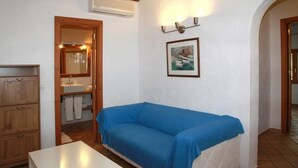 A room with a blue sofa, wooden cabinets, a sink, and a framed picture on the wall. - Finca Son Guardiola (Llucmajor)