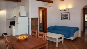 A compact living space with a wooden dining table, a blue-covered sofa, and a white refrigerator. - Finca Son Guardiola (Llucmajor)