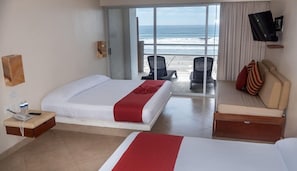 Une chambre d’hôtel avec un lit, un canapé, une télévision et vue sur l’océan.