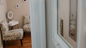 Een kamer met gestreepte stoelen, een klein rond tafeltje en decoratieve spiegelwanden.